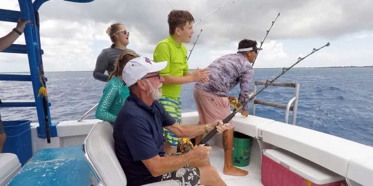 Familia divirtiéndose en un viaje de pesca en alta mar en Cozumel