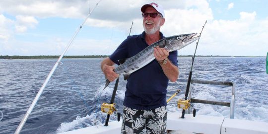 deep sea fishing photo of a Man holding a baracuda