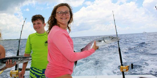 young girl in pink shirt catching a fish